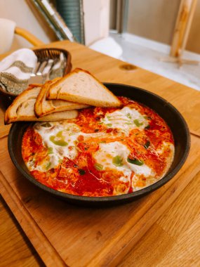 Nefis Shakshuka, sıcak bir kafe ortamında kızarmış ekmekle servis edilir.