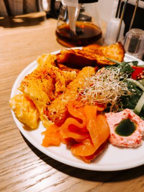 Delicious breakfast spread featuring eggs, smoked salmon, and fresh vegetables in a cozy setting