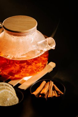 Warm black tea with spices and lemon slices arranged on a dark background