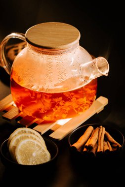 Beautiful black tea served with lemon and cinnamon on a wooden tray in a warm setting