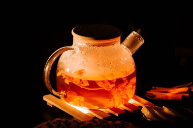 Warm black tea brewed in a clear teapot with steam rising during evening relaxation
