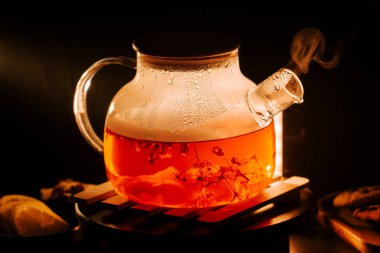 Enjoying black tea in an elegant teapot with floral accents and steam rising in warm light