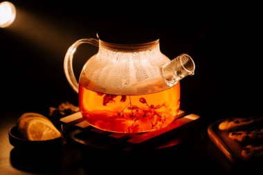 Brewing black tea with floral notes in a glass teapot at night