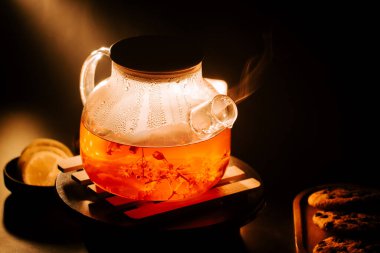 Delicious black tea brewing in a glass pot with steam rising on a cozy evening