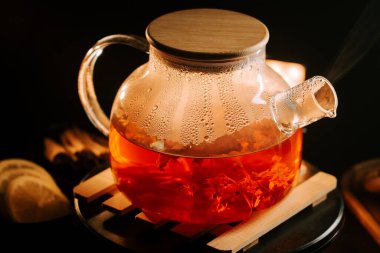 Brewing aromatic black tea in a glass teapot with steam rising in a cozy setting