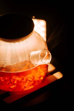 Enjoying black tea brewed in a clear kettle on a warm evening by the cozy light