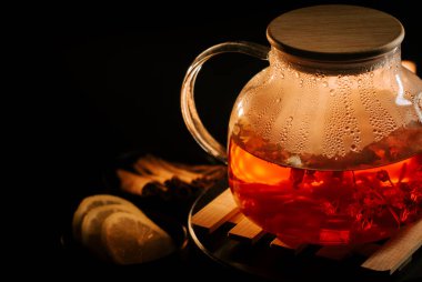 Warm black tea brewing with lemon slices and fresh herbs on a wooden tray