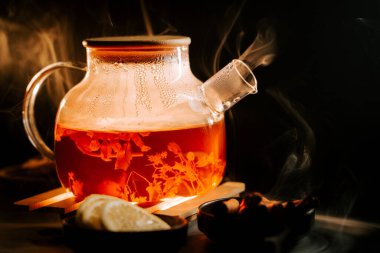 Warm black tea brewing with herbs and fruits in a cozy setting near candlelight