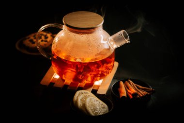 Warm black tea with spices and lemon served on a wooden tray in a cozy setting