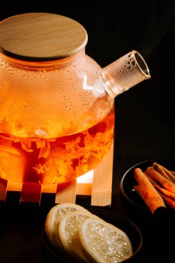 Warm black tea brewing with lemon slices and cinnamon sticks in a cozy setting