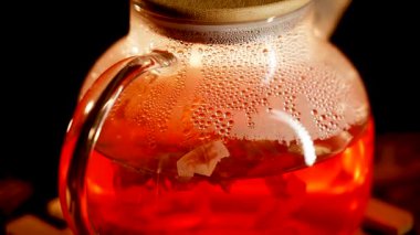Brewing rich black tea with steam rising in a clear kettle