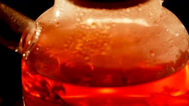 Brewing black tea with steam and bubbles in a glass teapot
