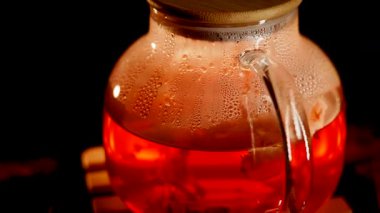 Enjoying fresh black tea brewed in a glass pot with steam rising in a cozy setting