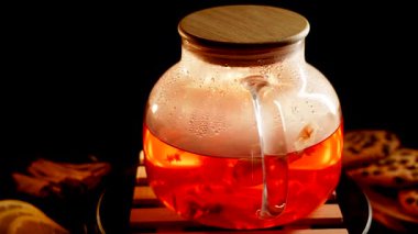 Brewing black tea in a glass teapot with aromatic herbs and spices