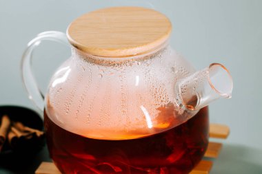 Brewing tea in a clear glass kettle with steam rising in a calm setting