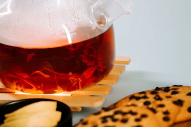 Freshly brewed tea served with cookies on a wooden tray with a light background