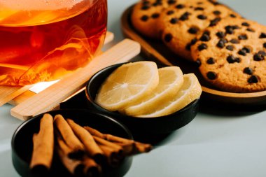 Warm tea with fresh lemon and chocolate chip cookies on a cozy table setting