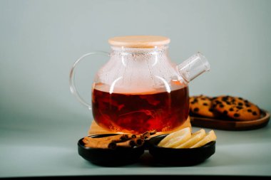Warm tea served with cookies and spices on a light background