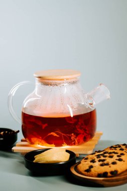 Enjoying a warm pot of herbal tea with biscuits on a cozy table setting