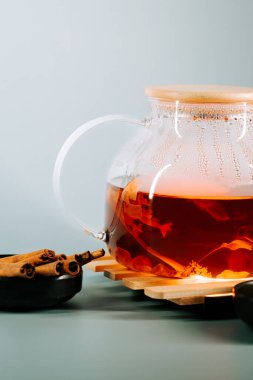 Brewing aromatic tea in a glass pot with cinnamon sticks on a wooden coaster