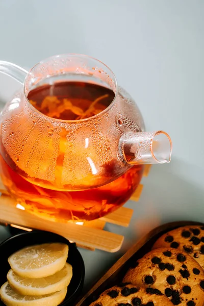 Warm tea brewing with lemon slices and a sweet pastry on a wooden tray