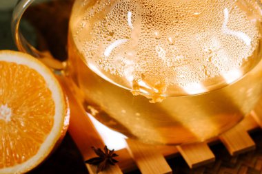 Brewed green tea with citrus and spices on a wooden surface in a cozy setting