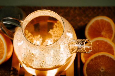 Brewing green tea with fresh oranges in a warm kitchen setting at dusk