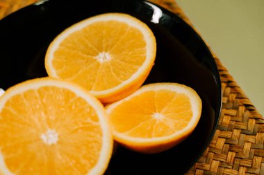 Sağlıklı bir atıştırmalık veya tatlı için siyah bir tabakta taze dilimlenmiş portakallar.