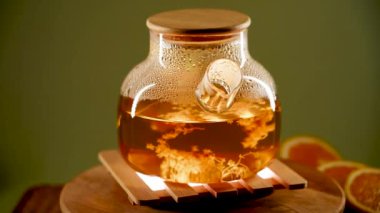 Sıcak bir ortamda buharlı yeşil çay demleyen cam çaydanlık.