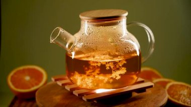 Yeşil çay buharlı cam çaydanlık sıcak bir tahtanın üzerinde yüzüyor.