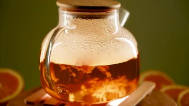 Narenciye aksanlı cam çaydanlıkta taze yeşil çayın tadını çıkarıyorum.