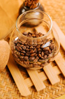 Coffee beans in a glass jar on a wooden mat with a natural background
