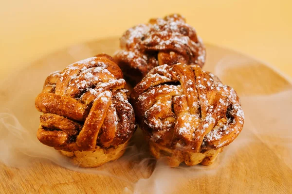 Freshly baked cinnamon rolls on a wooden plate with powdered sugar for an inviting dessert display