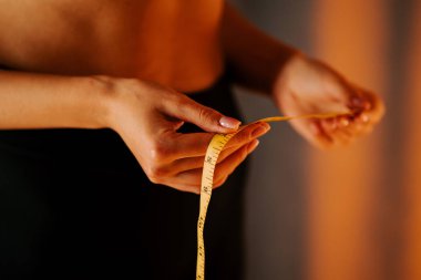 Gece boyunca hafifçe aydınlatılmış bir odada bir mezura ile bel ölçüsü