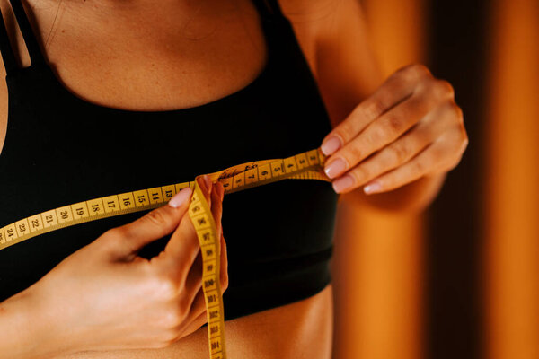 Измерение размера груди с помощью измерительной ленты в уютной внутренней обстановке