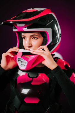 Motokros binicisi içeride parlak pembe kıyafetler giymeye hazırlanıyor.
