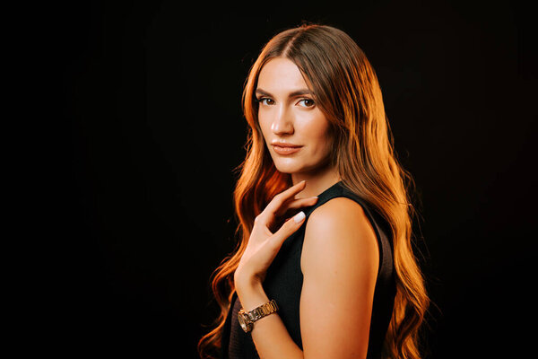 Model poses gracefully with long hair under dramatic lighting in a studio setting