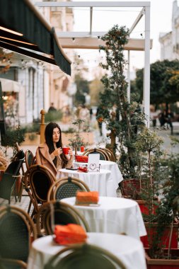 Gecenin erken saatlerinde büyüleyici bir caddede kahve içen bir kadın.