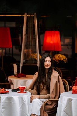 Kadın, alacakaranlıkta kırmızı lambalar olan eski ve büyüleyici bir İtalyan kahve dükkanında kahveden hoşlanıyor.