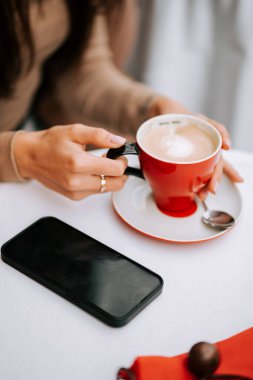 Akıllı telefonunu kullanarak eski bir İtalyan kahve dükkanında kahve içen bir kadın.