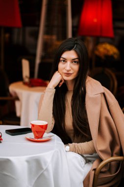 Sıcak bir atmosferi olan büyüleyici bir İtalyan kahve dükkanında kahve içen bir kadın.
