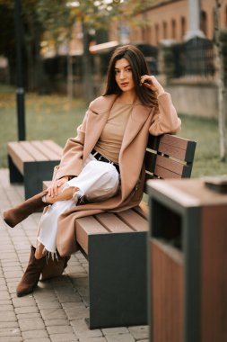 Genç bir kadın, sonbahar öğleden sonra şık bir kıyafetle parkta huzurlu bir anın tadını çıkarıyor.