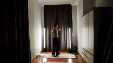 Yumuşak ışıklandırma ve karanlık perdelerle rahat bir odada tek başına dans etmek