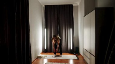 Rahat bir odada hafif ışıklandırma ve yoga ekipmanlarıyla evde çalışma.