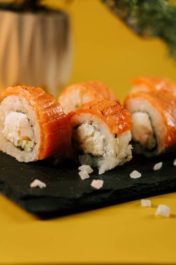 Siyah tabakta taze somon ve krem peynirli suşi ruloları.