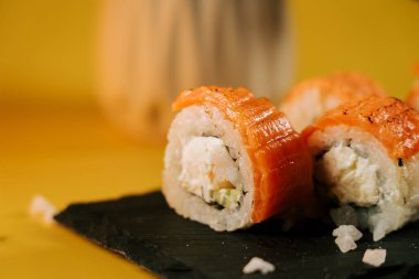 Siyah tabakta somon ve krem peynirli lezzetli suşi ruloları.
