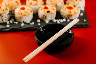 Soya sosu ve kırmızı masada çubuklarla servis edilen lezzetli suşi ruloları.