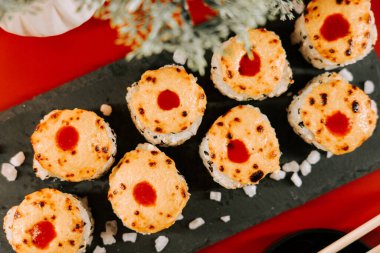 Siyah taş tabakta servis edilen çıtır çıtır suşi ruloları.