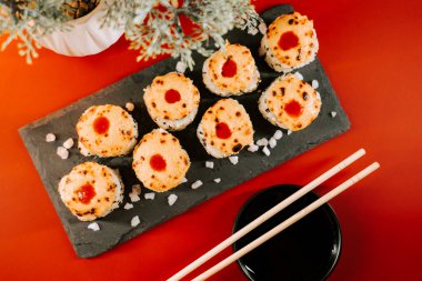 Lezzetli suşi ruloları yemek çubukları ve sos ile servis edilir.