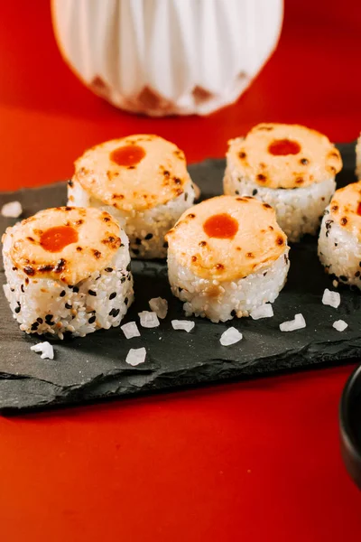 Siyah bir tabakta servis edilen lezzetli suşi dürümleri ve canlı bir arka plan.
